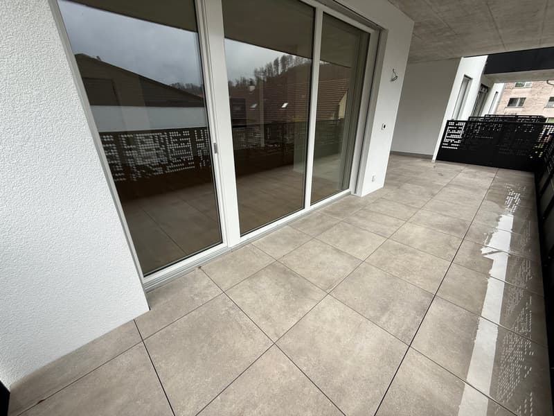 Balcony with sliding glass doors, tiled floor, black railings