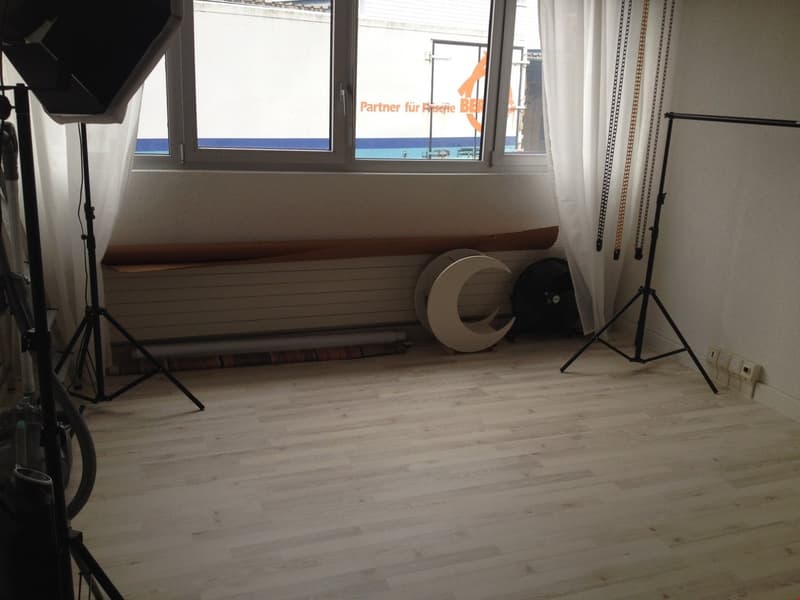 wooden floor, bright room, large window, white curtains, tripod stands, white crescent moon structure, power outlets, heater below window