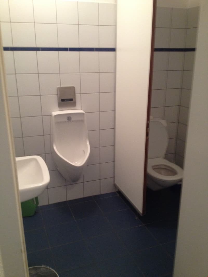A small bathroom with a urinal, toilet, sink, and tile flooring.