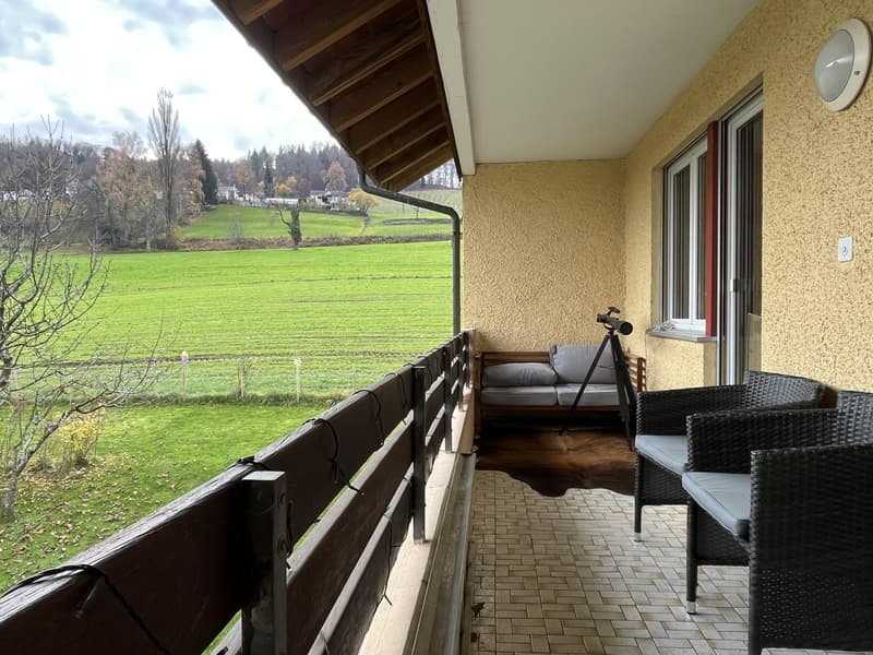 wooden railing, tiles, patio with a couch, chairs, and a telescope, a wall lamp
