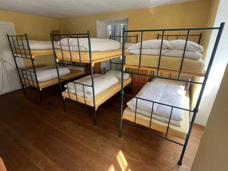 room with 4 bunk beds, wooden floor, yellow walls, white door