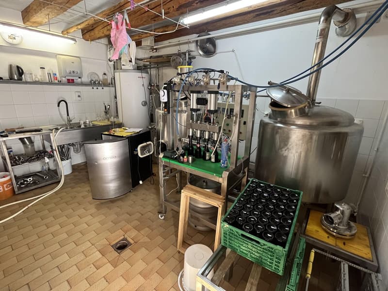 A commercial kitchen for a beverage production plant with several tanks, machinery, and bottles
