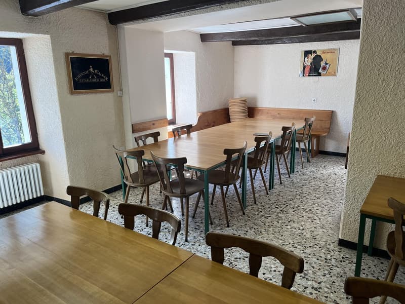 A room with tables and chairs for dining, a wooden bench, and picture frames on the wall