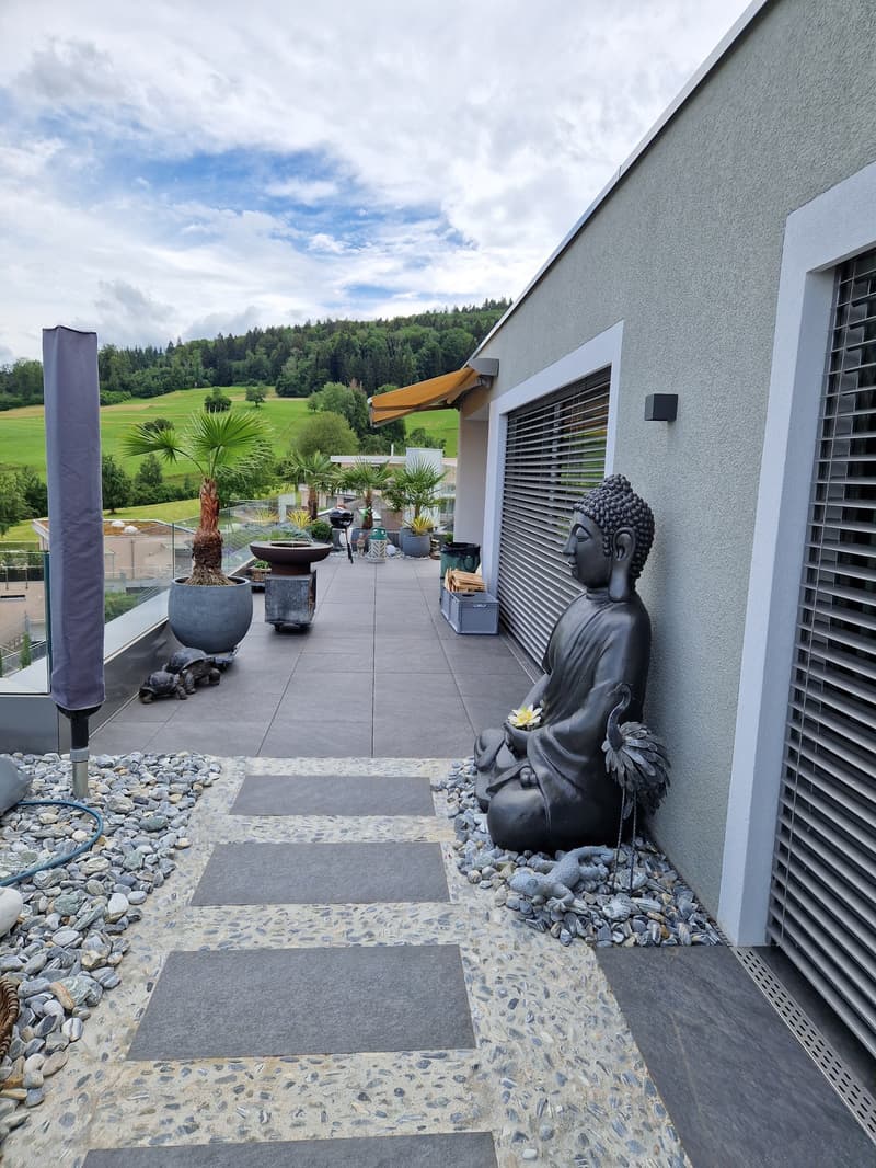 Balcony with stone tiles, Buddha statue, palm tree, flower pots, large window