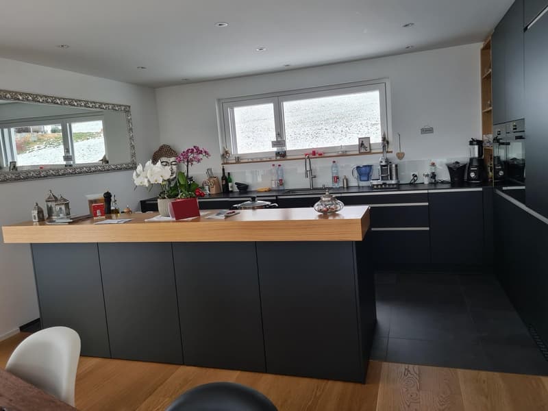 modern kitchen with a wooden counter, black cabinets, white walls, a sink with a faucet, and a window