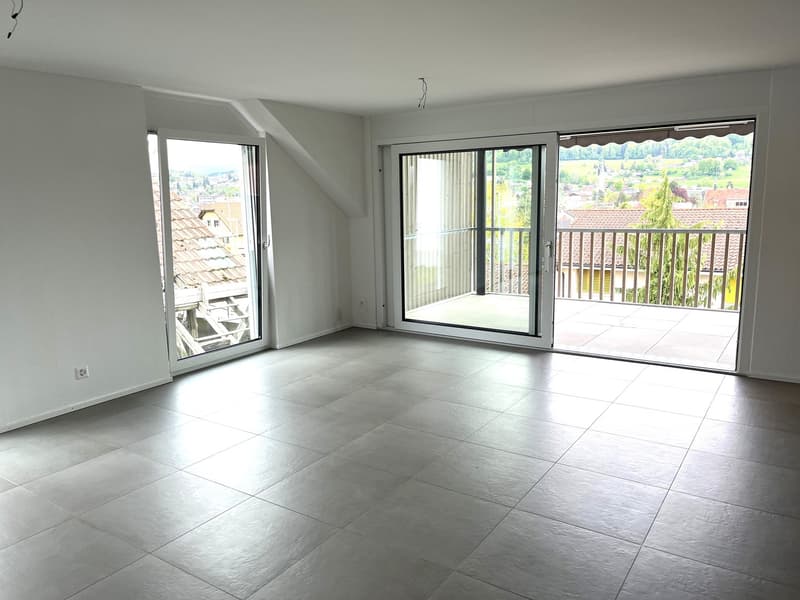 empty room, white walls, tiled floor, large sliding glass doors leading to balcony, power outlet on wall