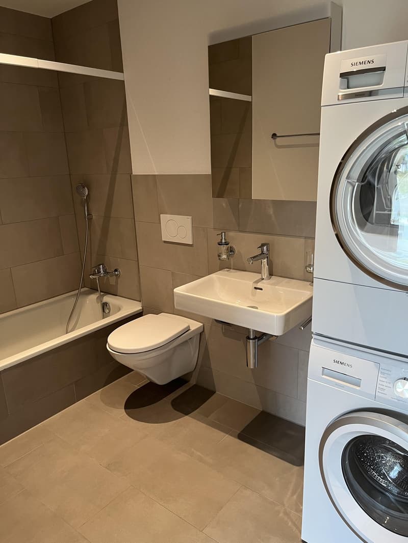 Bathroom with bathtub, toilet, sink, and washing machine and dryer