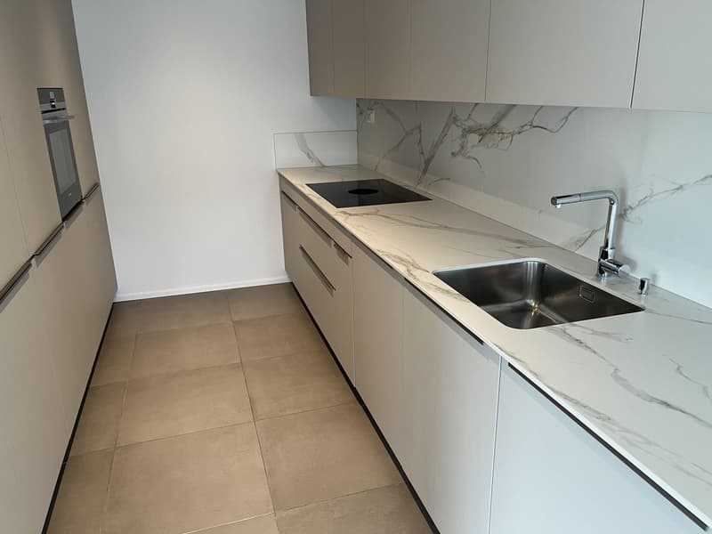 modern kitchen, white marble countertops, stainless steel sink, black induction cooktop, white cabinets, tiled floor, built-in oven