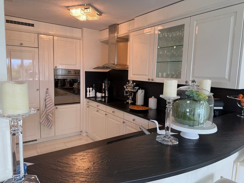 modern kitchen with granite countertops, white cabinets, stainless steel appliances, black tiled backsplash, kitchen island with seating, chandelier, open shelving, dishwasher, microwave, and washing machine