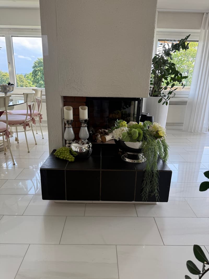 white tiled floor, fireplace with a decorative setup, white curtains, potted plants, table with chairs