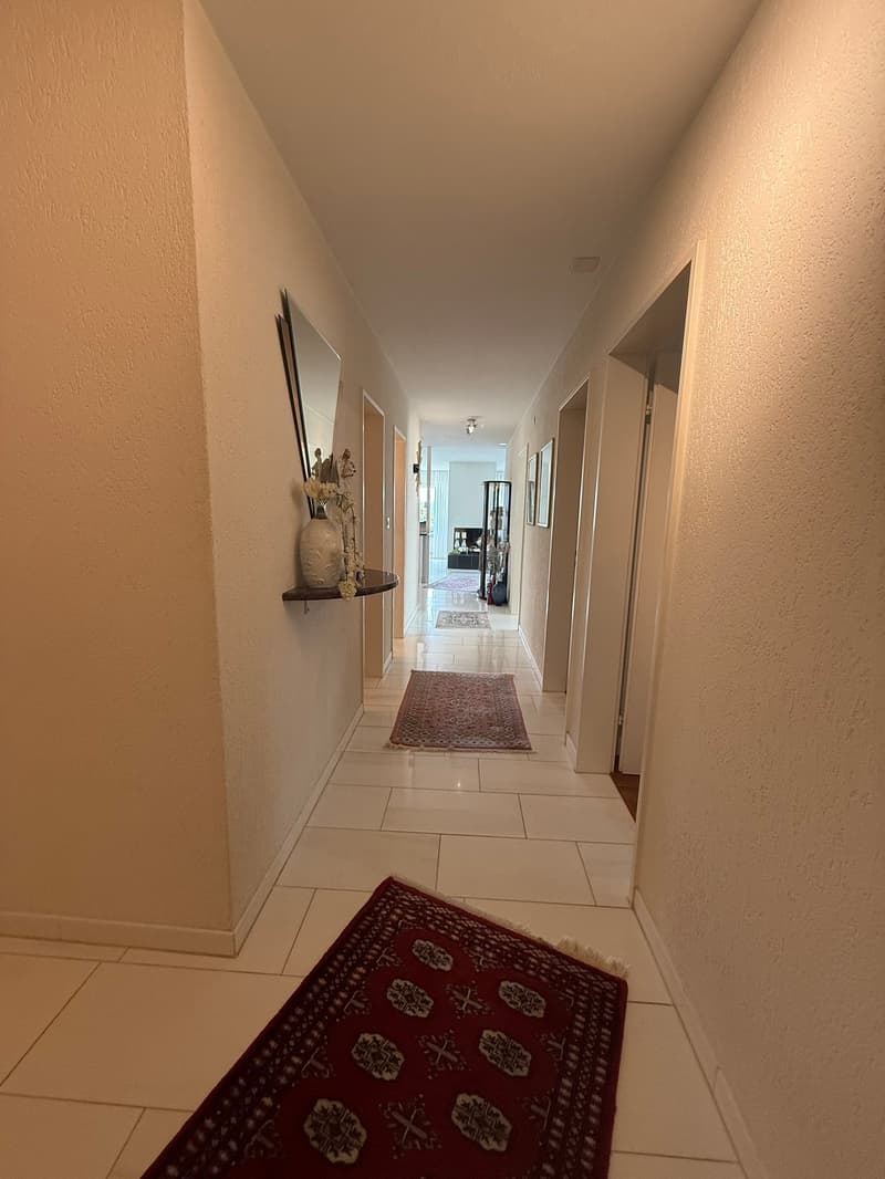 tiled hallway with carpeted floor, wall decorations, and mirror