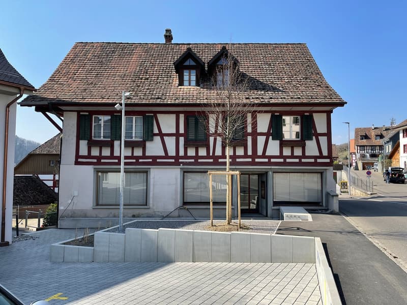 two story house, red tiled roof, red and white color scheme, shutters on windows, paved front area