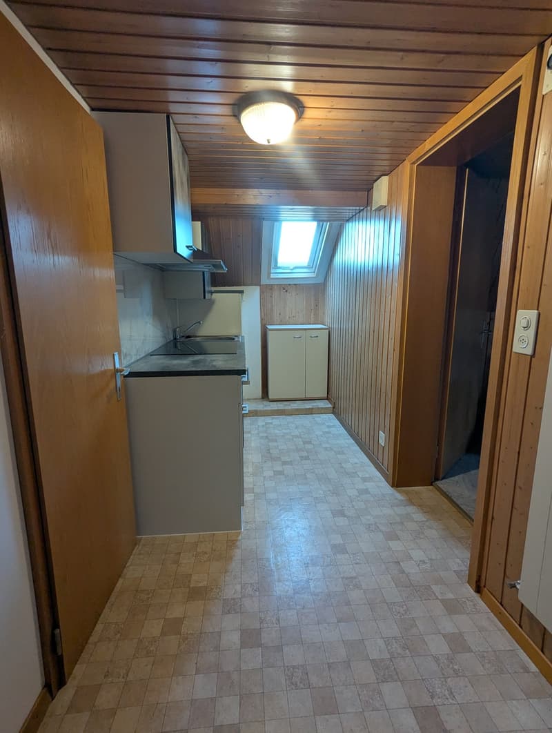 Empty kitchen with tiled floor, wooden ceiling, sink, cabinets, and a window.