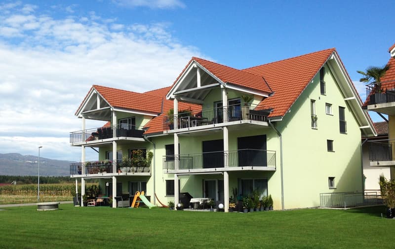 3 story house, yellow exterior, red roof, multiple balconies, garden, slide, trash bin