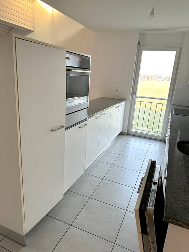 modern kitchen with white cabinets, stainless steel appliances, tiled floor, balcony with railings