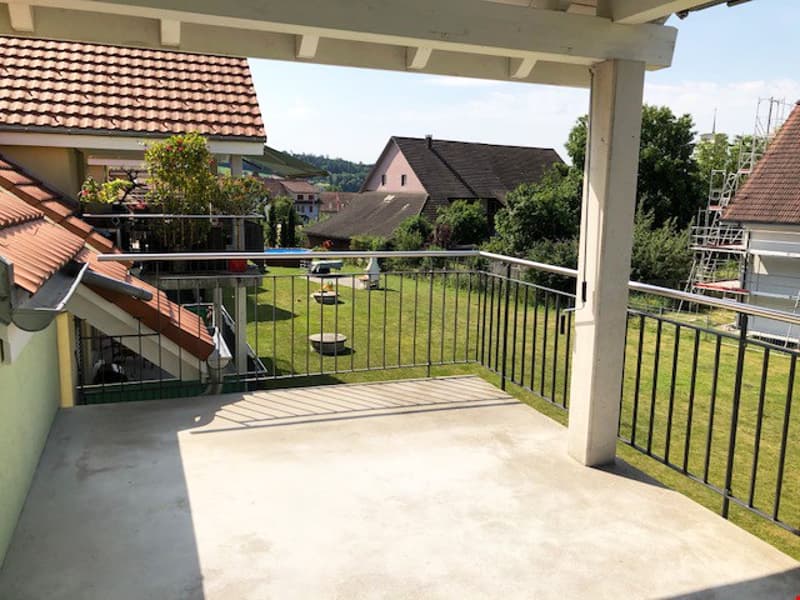 covered balcony with metal railings, overlooking a grassy area with a pool