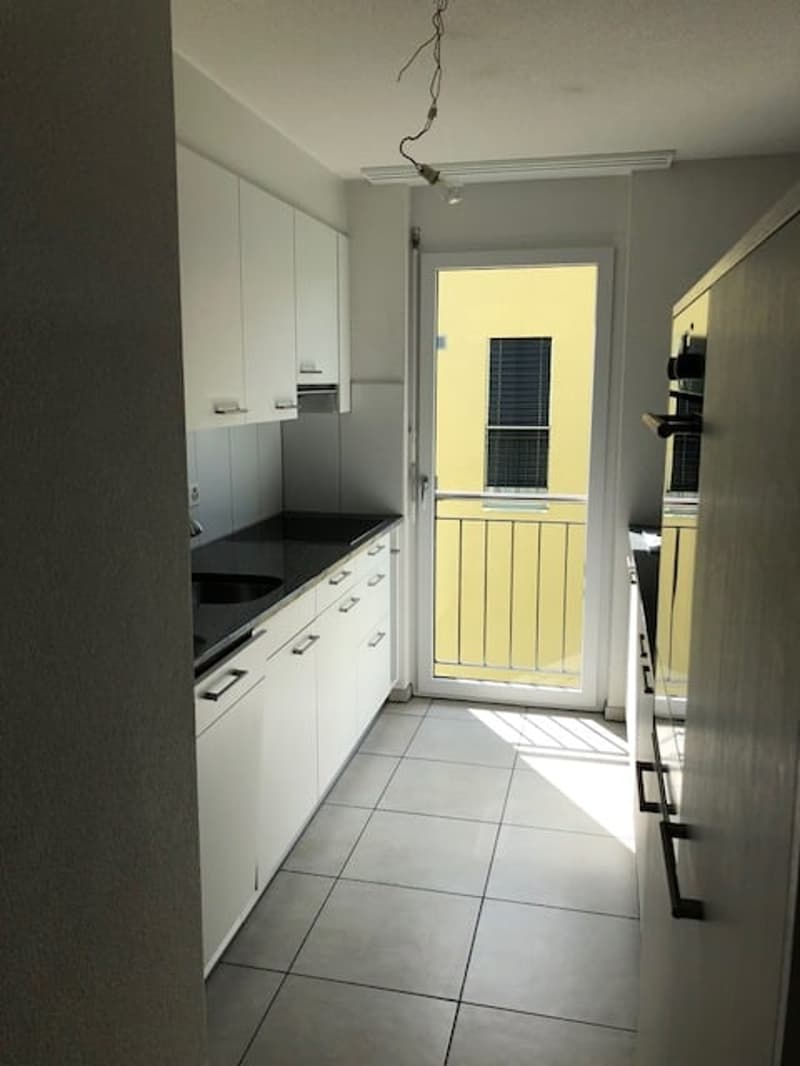 modern kitchen with white cabinets, black countertop, sink, balcony with railings