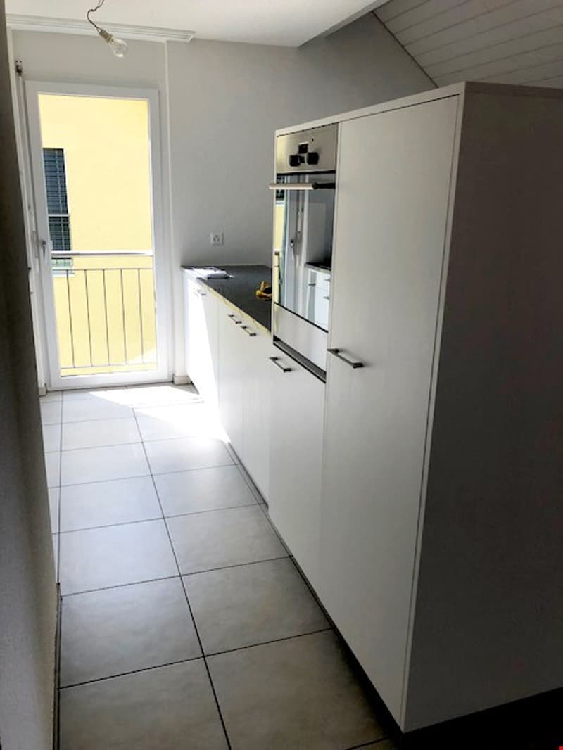 modern kitchen with white cabinets, tiled floor, built-in oven, balcony