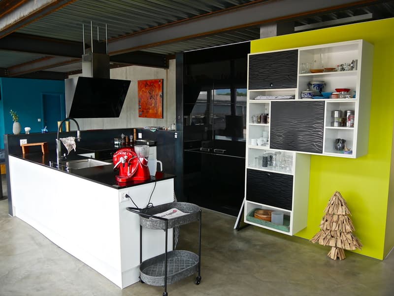 modern kitchen with black countertops, white cabinets, red mixer, white shelves, yellow wall, blue wall, wooden table, white sink, faucet, power outlet, small cart, metal ceiling