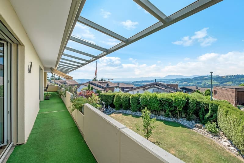 Balcony with green carpet, metal railing, glass wall, view of the mountains