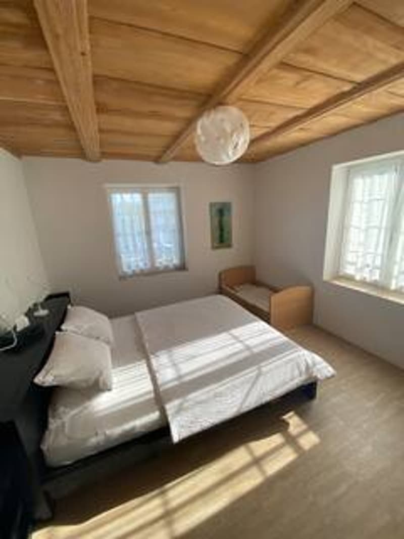 Bedroom with wooden ceiling, bed, crib, windows, wooden floor