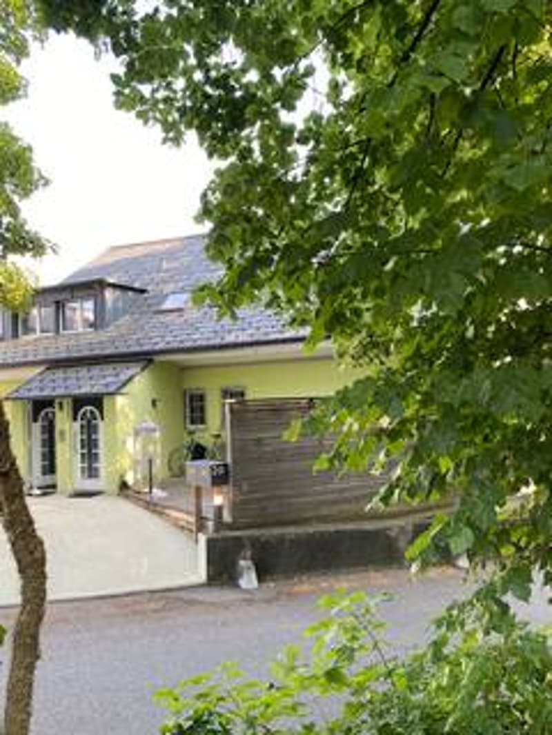 2 story house, yellow exterior, gray roof, driveway, garage, wooden fence, trees