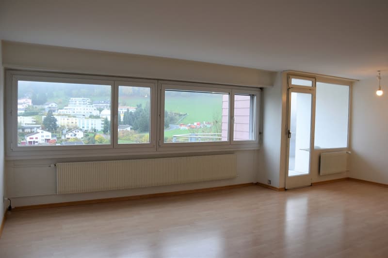empty room, wooden floor, large windows, white walls, white radiators, door leading to another room