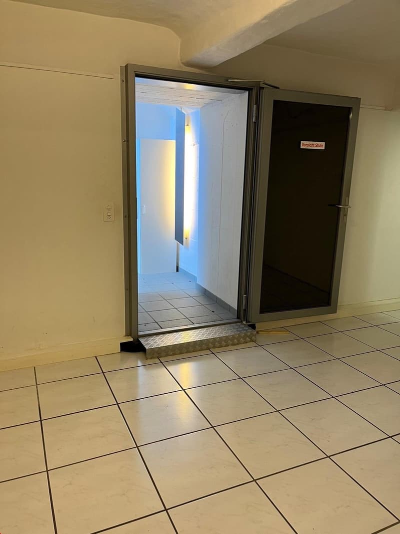 An open double door leading to a tiled hallway, a switch on the wall