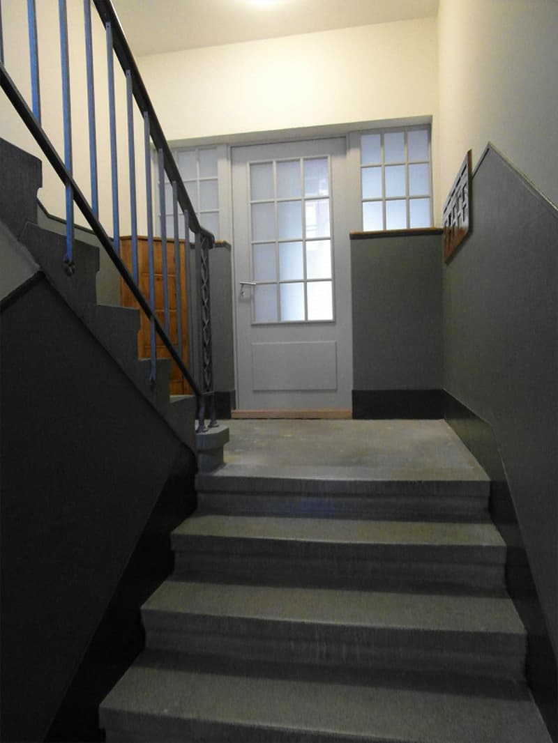 stairs leading up to the entrance, white door, wooden frame, gray walls