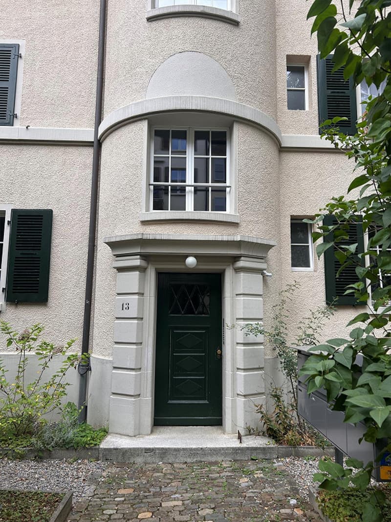 Cobblestone entry, green door, arched window above, brick-fronted, two windows to either side