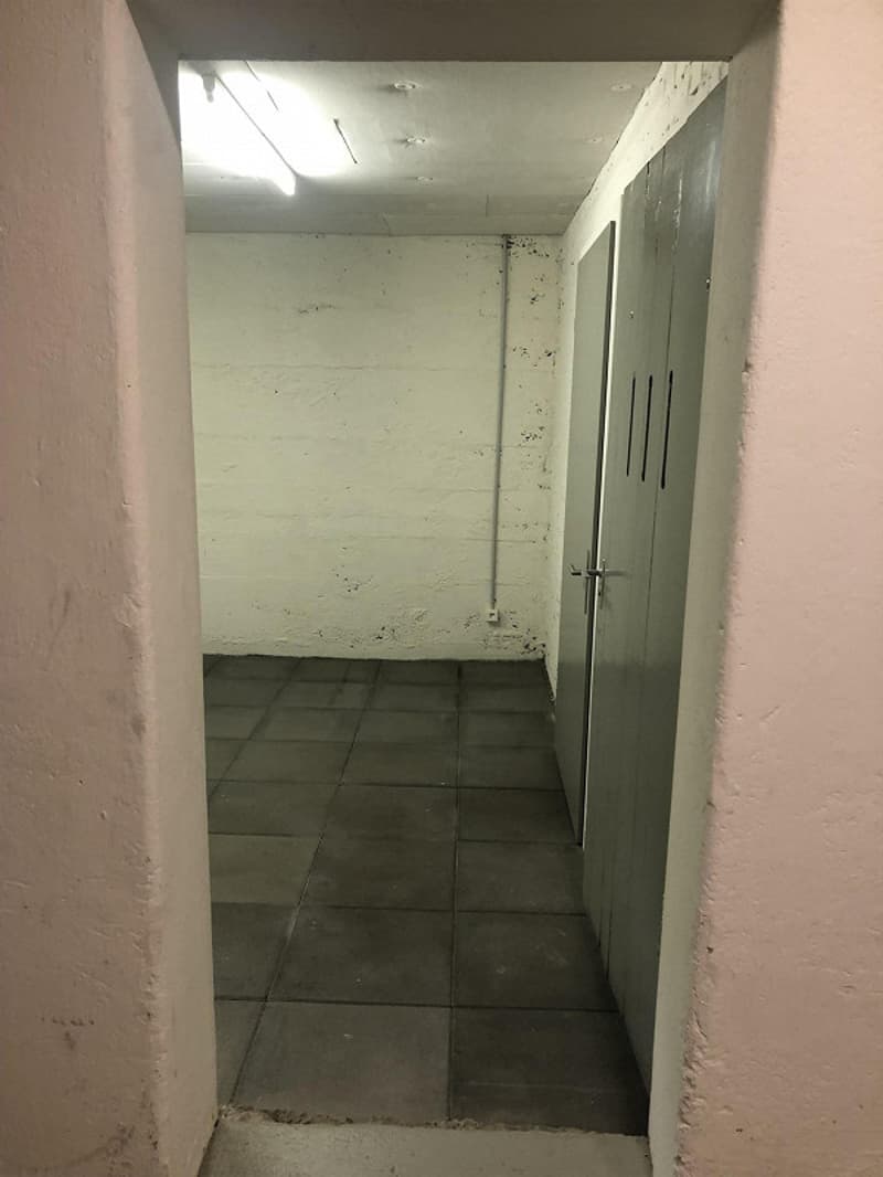 Empty room, tiled floor, white walls, metal doors, fluorescent light