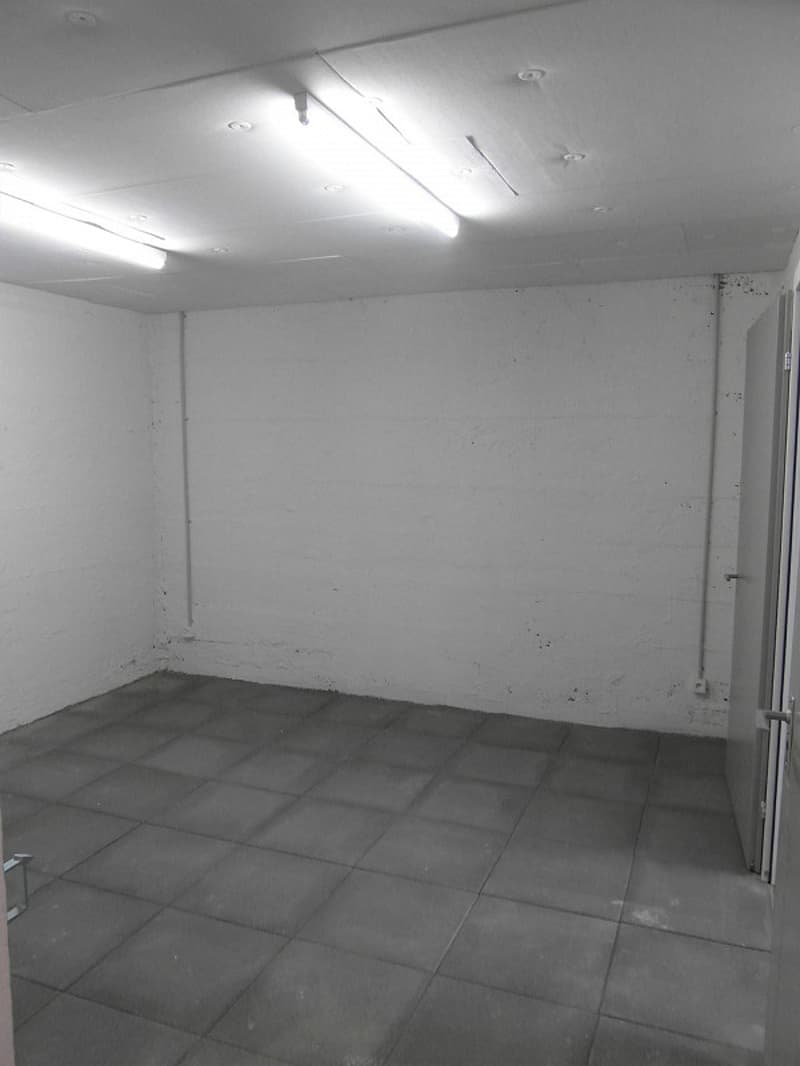 empty room with grey tiles and white walls, one door on the right side