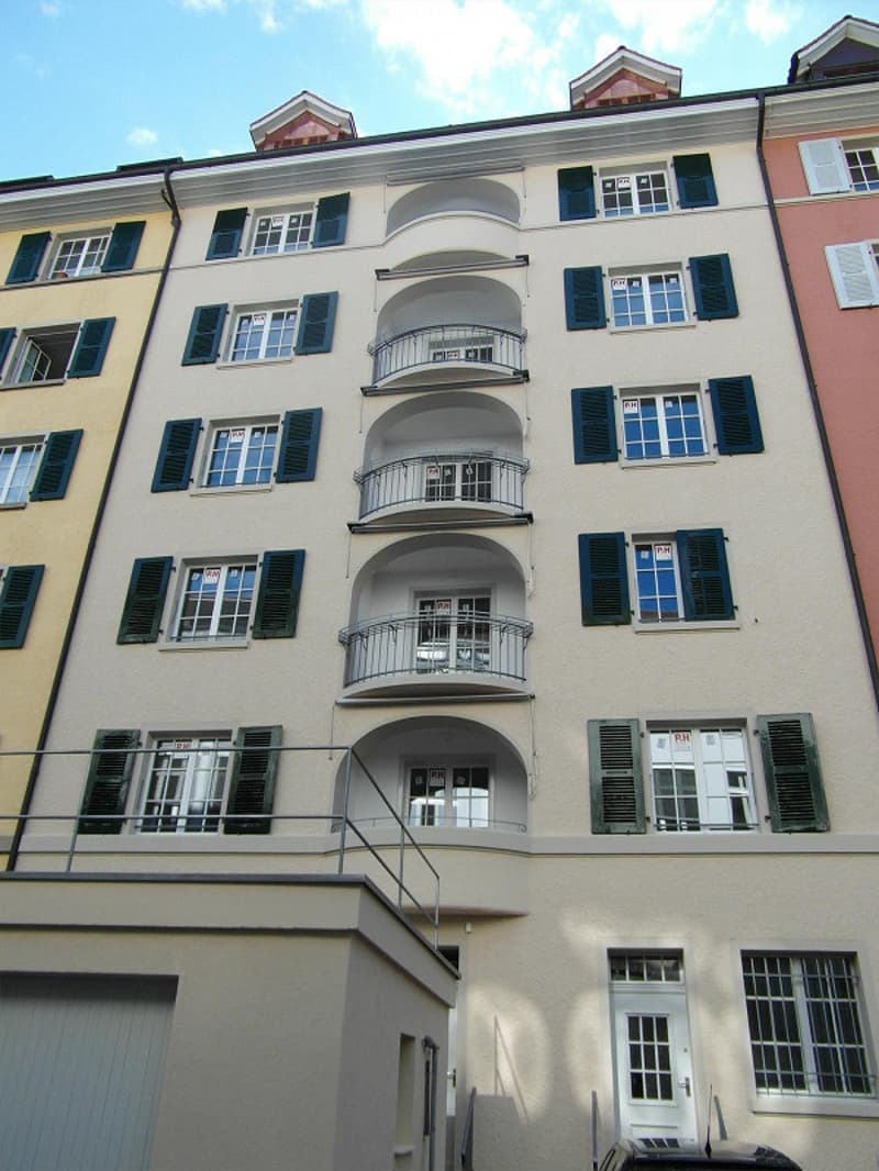 6-story building, balconies on multiple floors, green shutters, beige and pink exterior