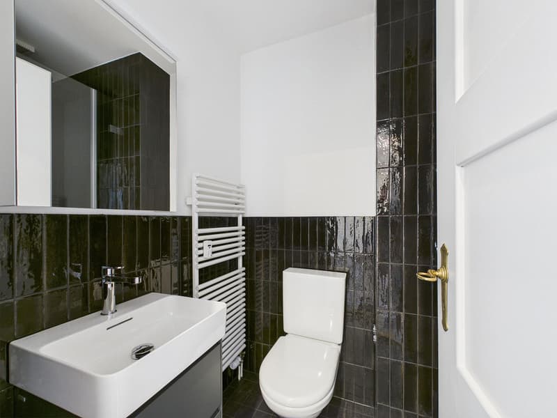 white sink, white toilet, black tiles, white towel rack
