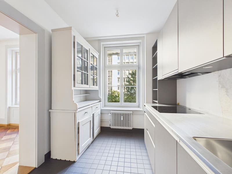 modern kitchen with white cabinets, tiled floor, stainless steel sink, window with view