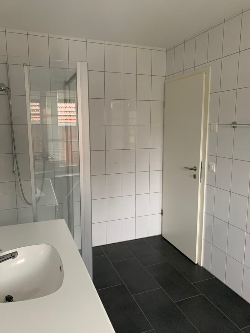 Empty bathroom with shower, sink, and toilet