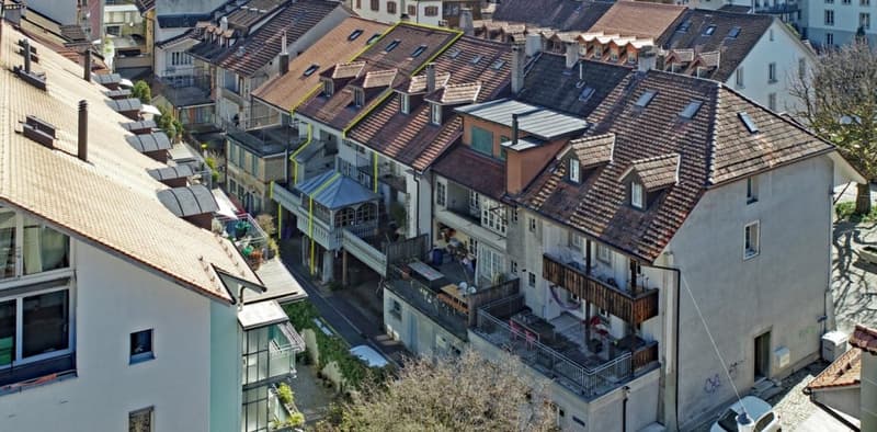 Aerial view of a row of terraced houses with balconies, brown roofs, and multiple windows