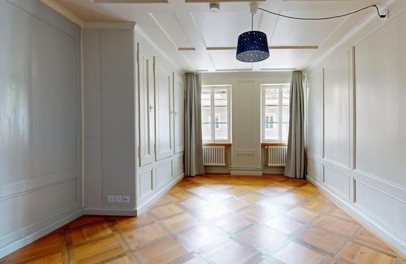 Empty room, wooden floor, white walls, two windows, radiators, ceiling lamp