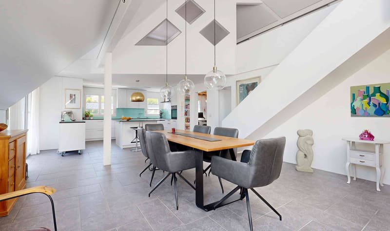 modern open-plan living room with dining area, kitchen with island, white walls, wooden floor, gray chairs, dining table, pendant lights