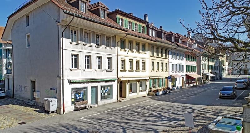3 story building, multiple windows, street view, parked cars, benches, trash bin, tree