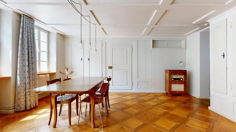 Dining room with wooden floor, white walls, wooden table, chairs, radiator, wooden cabinet, pendant lights