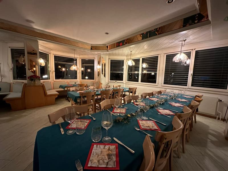 long dining table, chairs, wine glasses, decorated placemats, long bench, lamps, windows, radiator