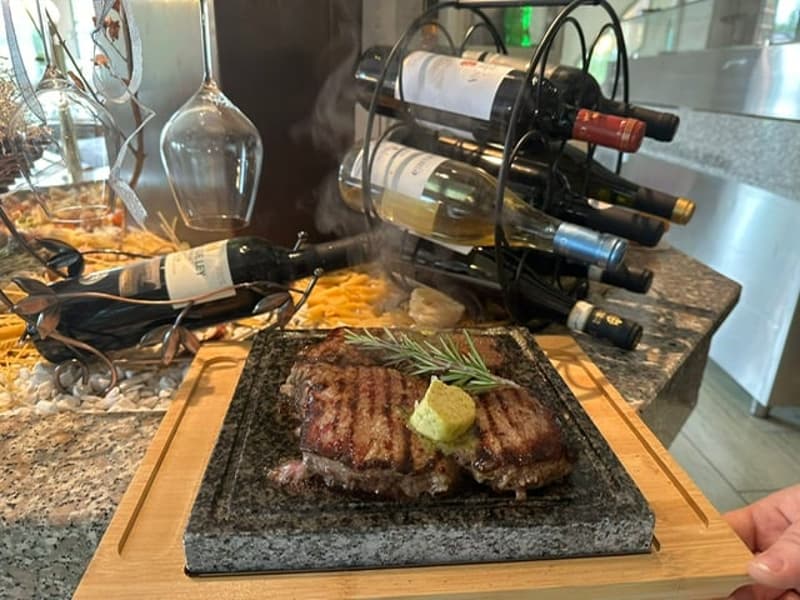Stone countertop, wine bottles, steaks on stone slab, wood cutting board, granite countertops, kitchen area