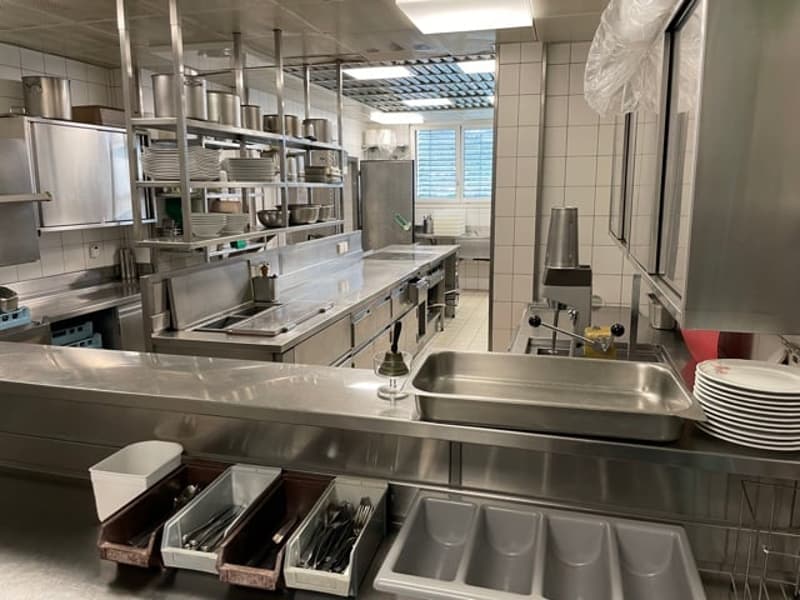 Well-equipped kitchen with stainless steel countertops, appliances, utensils, and organized shelves.
