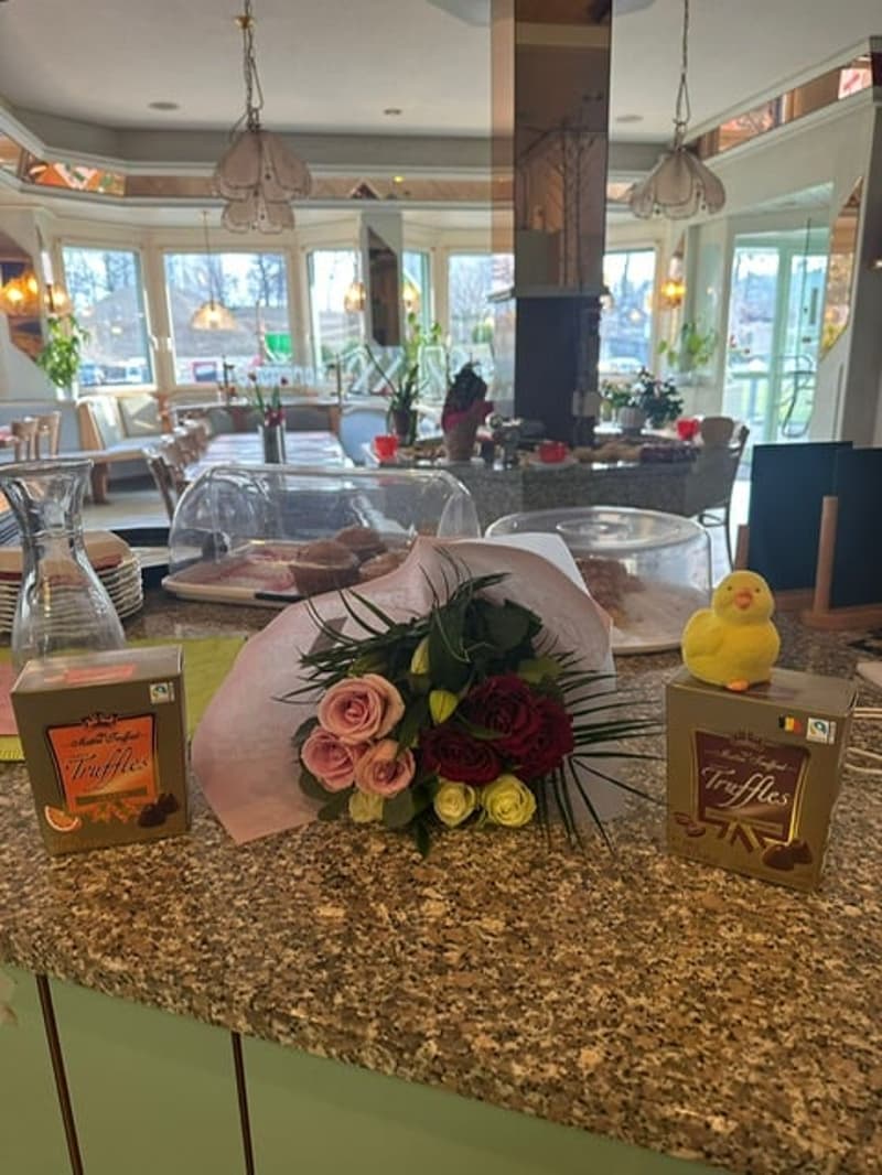 Table with flowers, chocolates, rubber duck, and a glass jar, and a view of the outside