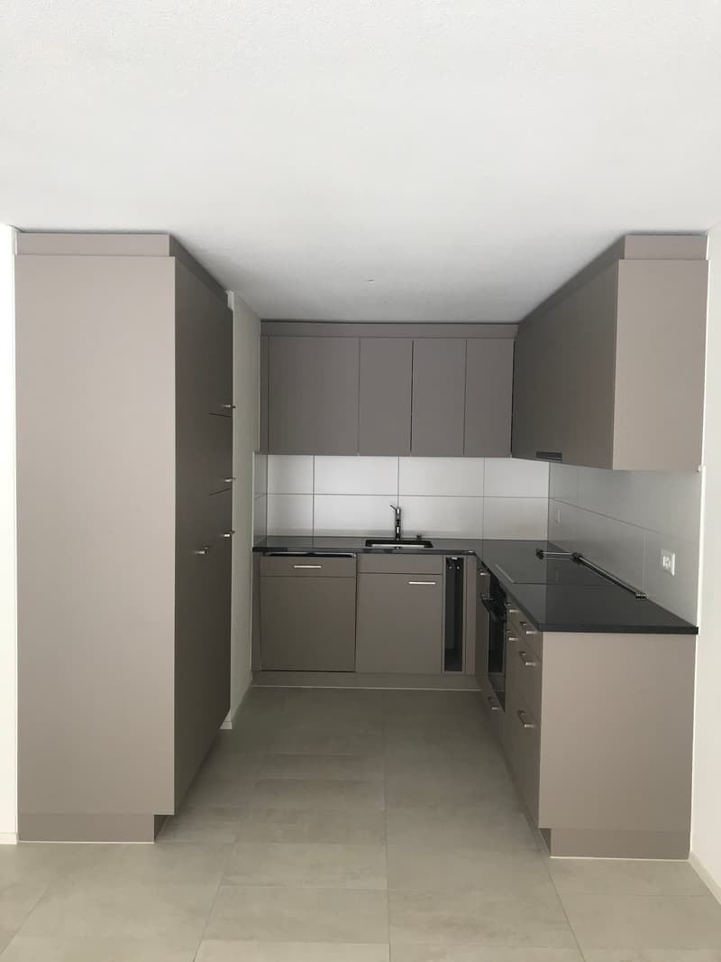 modern kitchen with gray cabinets, black countertops, stainless steel sink, dishwasher, and tiled floor