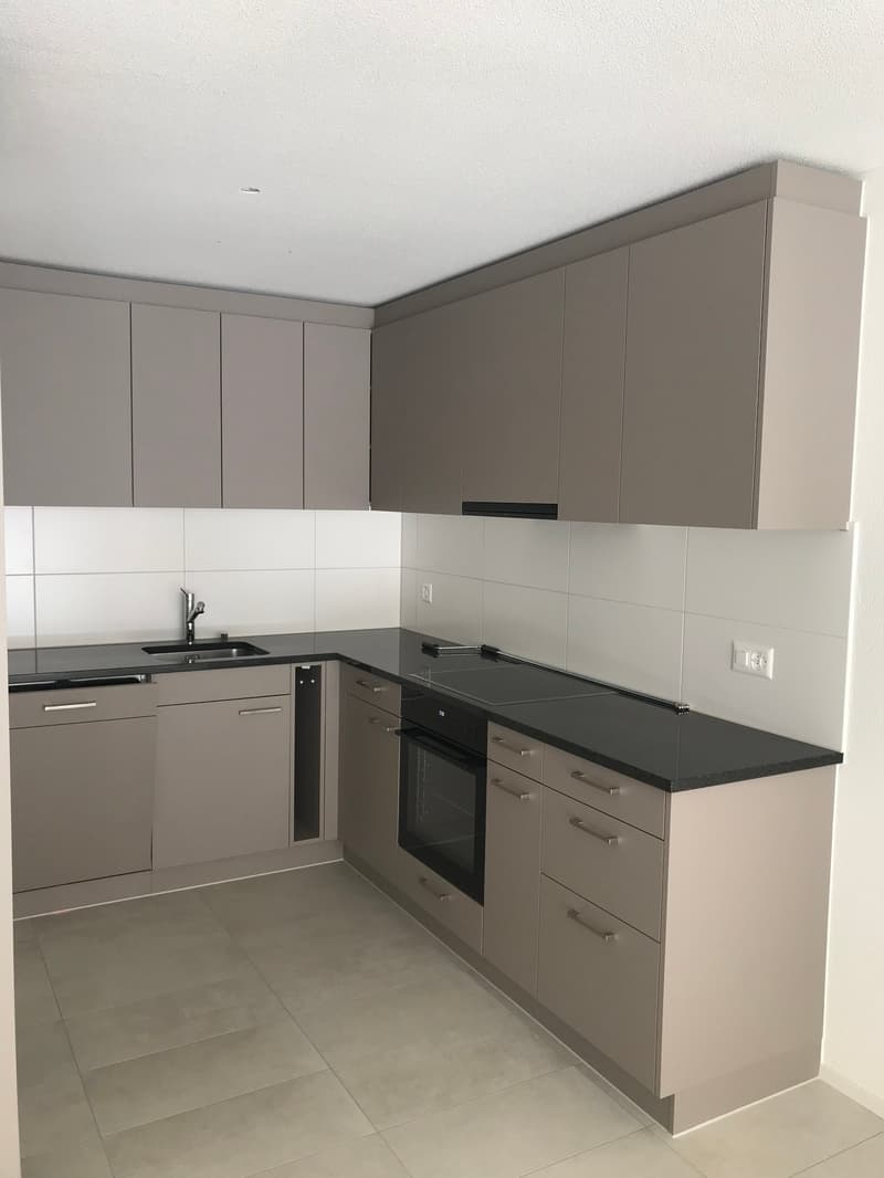 modern kitchen with gray cabinets, black countertops, stainless steel sink, gas stove, oven, dishwasher, power outlets, and tiled floor