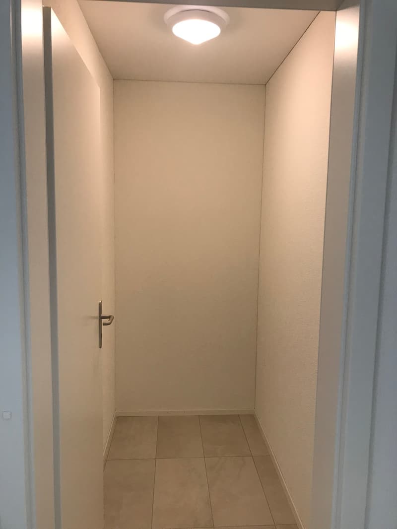 Empty room with white walls, tiled floor, and a door