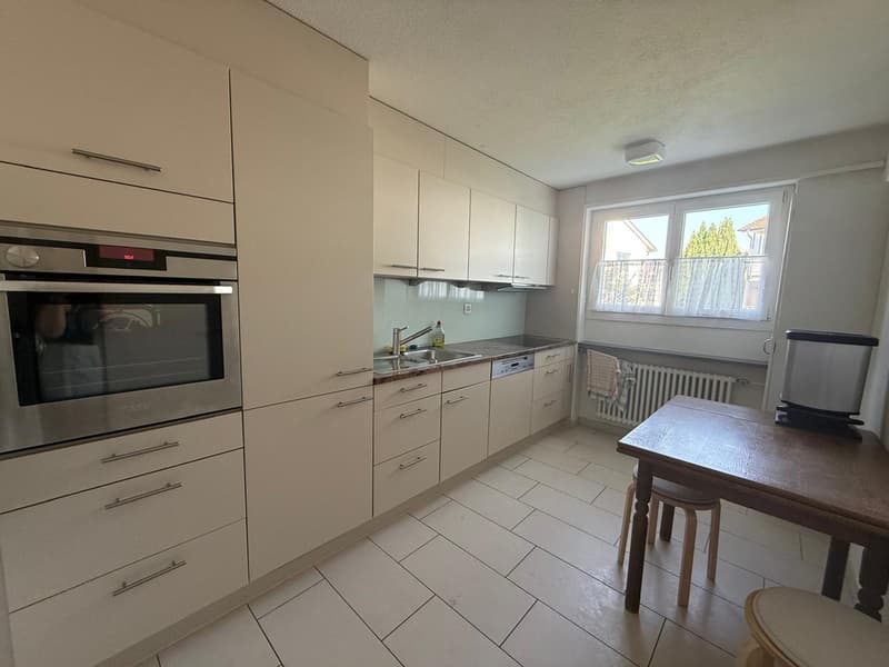 Modern kitchen with white cabinets, stainless steel appliances, sink, oven, dishwasher, window with curtains, tiled floor