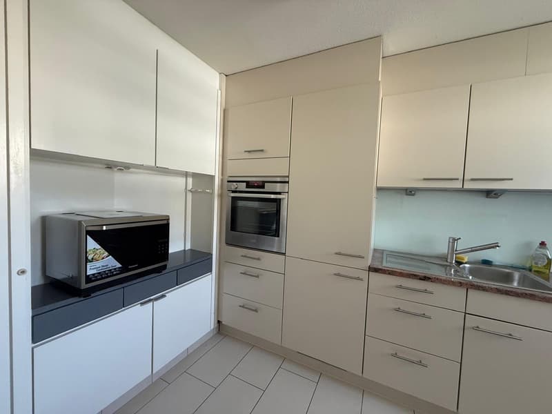 Modern kitchen with white cabinets, tiled floor, oven, microwave, sink, and dishwasher